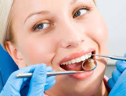Woman smiles as dentist checks her teeth